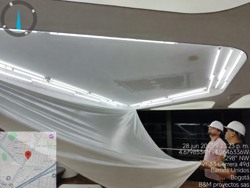 Operarios de B&M Proyectos manipulando la membrana Tensoflex® descolgada, con la estructura del cielo raso y la iluminación LED perimetral a la vista.